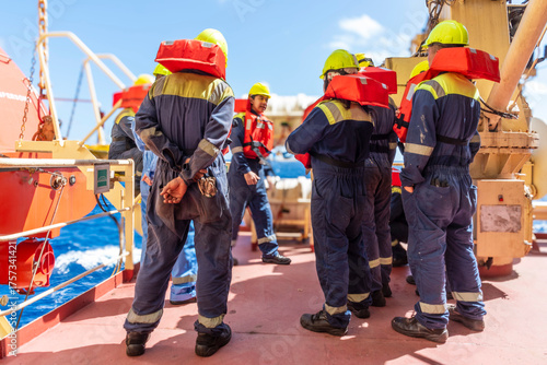 Crew members on a merchant ship are gathered on deck for an abandon vessel drill. 