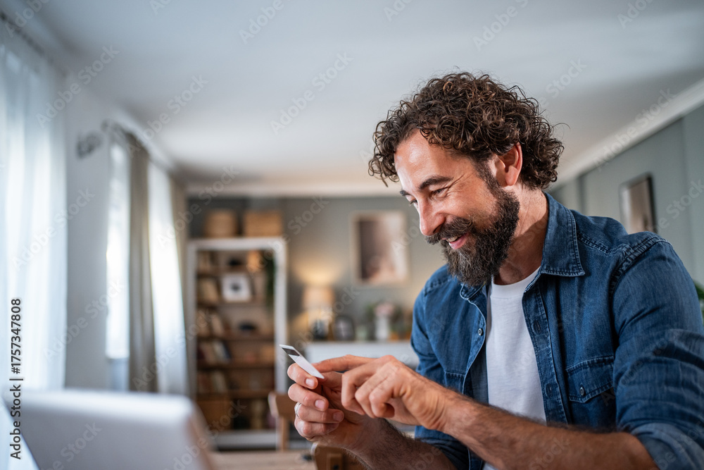 Fototapeta premium Man using credit card for online payment at home