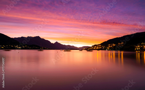 Vibrant sunset paints the sky over tranquil lake