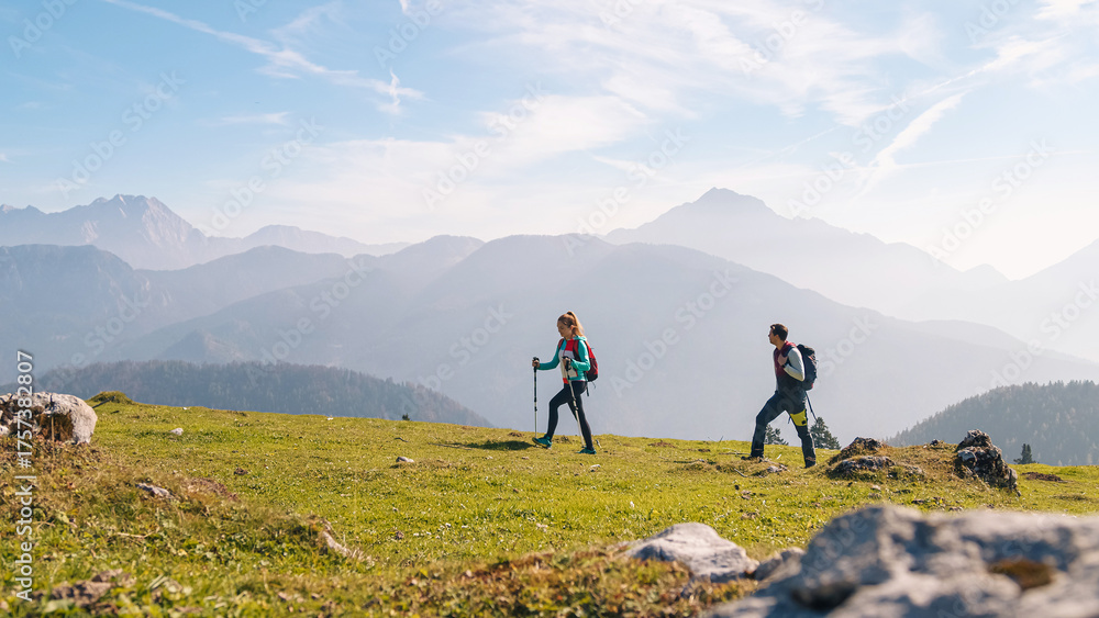 Obraz premium Two hikers explore a beautiful mountain landscape under a clear sky, enjoying the serene environment and fresh air.