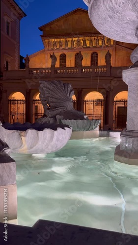 detail of the fountain in Piazza di Santa Maria in Trastevere with the illuminated facade of the basilica in the background