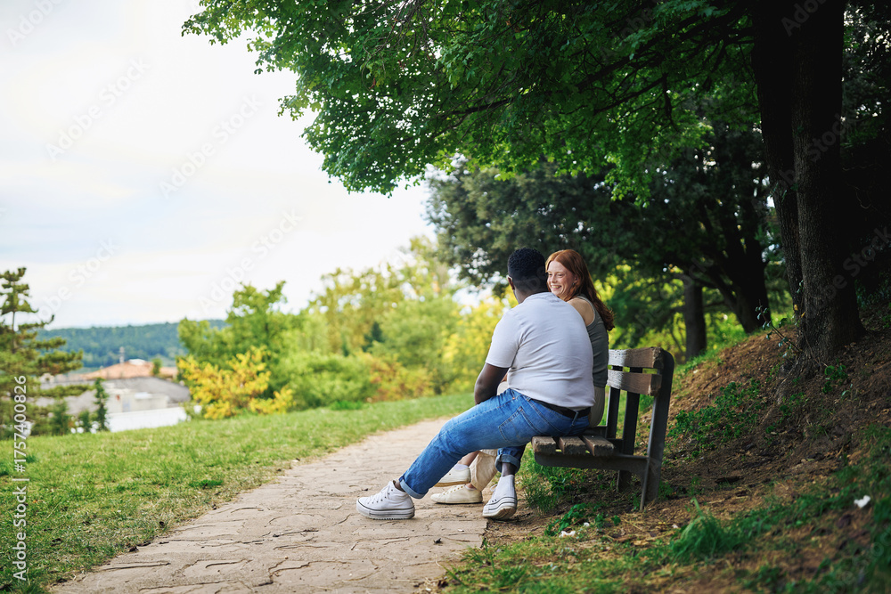 Obraz premium Young couple sitting on a park bench enjoying nature