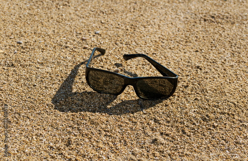 black sunglasses left on sand beach