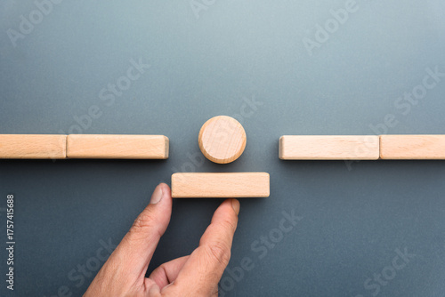A symbolic image showing a hand about to place a missing block as a round piece prepares to cross, representing team collaboration and strategic problem solving