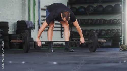 Mid adult athletic man with beard performing barbell snatch exercise