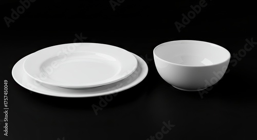 Two plates and a bowl stand on a black surface in a simple composition