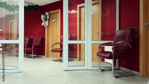 Bight corridor of a dental clinic with waiting chairs, doctors in protective clothing walking from room to room with patients. Human Health