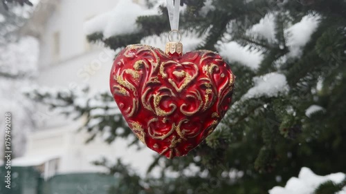 Christmas ornament heart shape red color hanging from pine branch under snow evoking warmth, romance, winter magic ideal for seasonal advertising, celebration backgrounds cozy holiday lifestyle vertic