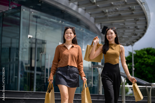 Two young asian women shopping carrying bags outdoors