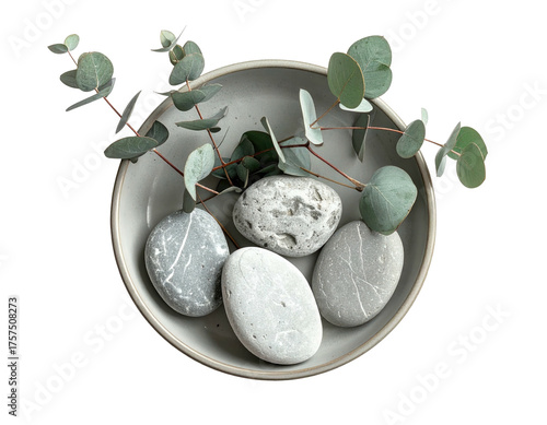Overhead shot of a gray ceramic bowl with smooth stones and sprigs of eucalyptus