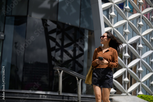 Woman walking urban city looking up carrying shopping bag