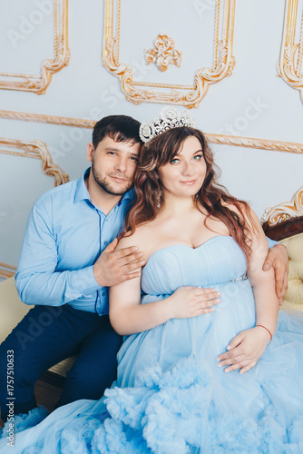husband hugs pregnant wife. pregnant girl in a lush blue dress. young man in a blue shirt. family photo session. 