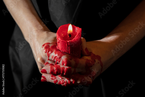 Waxplay. hand holding a candle by the fingertips while wax drips down