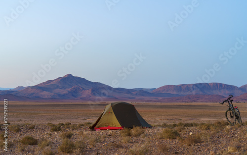 Desert camp under vast sky and mountains