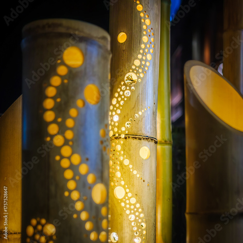 Close-up of handcrafted bamboo lanterns glowing at night, with intricate circular patterns carved into the bamboo creating a warm, artistic light display at a Japanese summer festival.