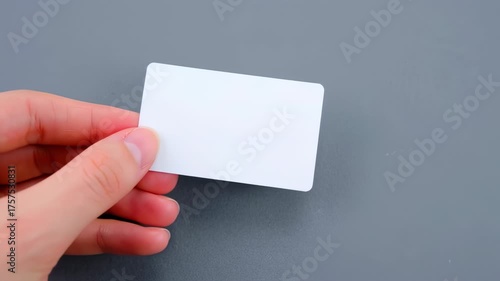 A blank white card held in a hand against a gray background