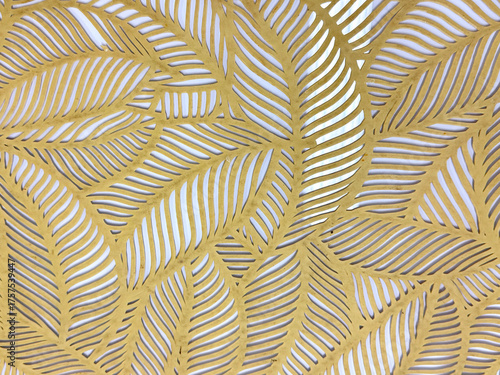 Close up of geometrical leaves shape pattern cutouts in metallic gold paint finish. 3D cutout laser cut foliage leaf shapes suitable for screens or divider. Seamless background texture.
