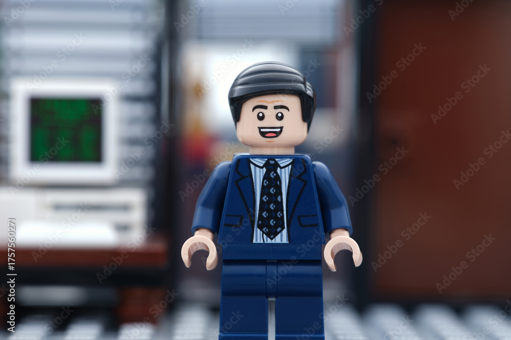 Naklejka premium Tambov, Russian Federation - October 16, 2025 A happy Lego businessman minifigure standing in his office in front of a computer.