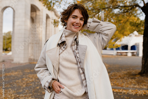pretty smiling woman walking in park in autumn clothes