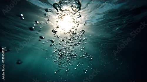 An underwater view of air bubbles rising towards the sunlit surface of deep blue-green water