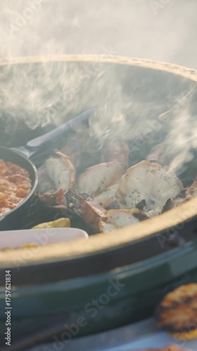 A green pot with food in it is on a table. The food includes shrimp, potatoes, and beans. The pot is steaming and the food looks delicious