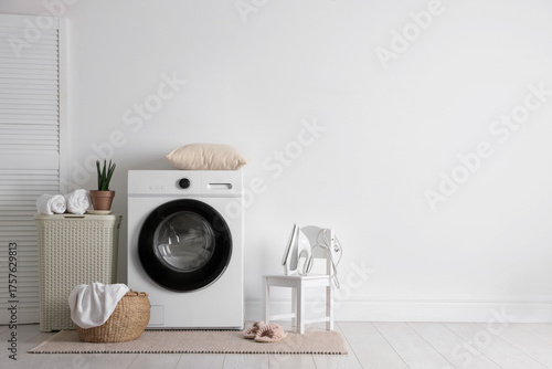 Laundry room interior with washing machine, basket and houseplant. Space for text