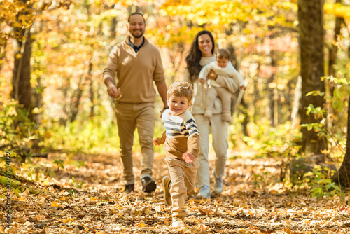 Beautiful young family on a walk in autumn forest