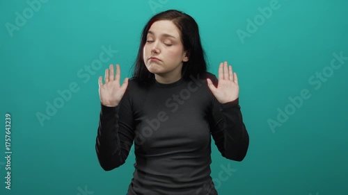 Woman brunette shrugging uncertainly against vibrant blue background emphasizing confusion and questioning with gestures.