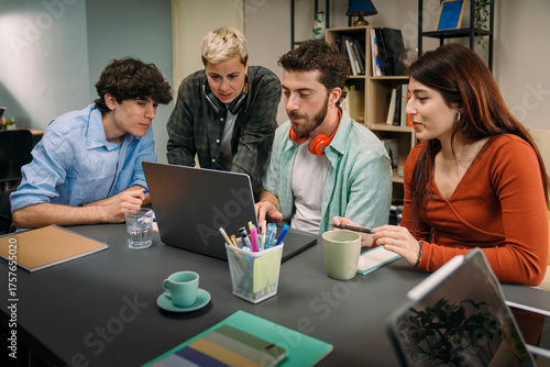 Group of diverse gen z students working together on laptop in a creative office. Concept of teamwork, collaboration, startup business, and brainstorming for a new project in a modern co-working space.
