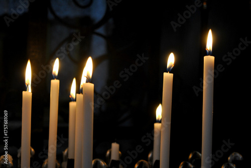 
a photo of several thin burning candles on a dark background