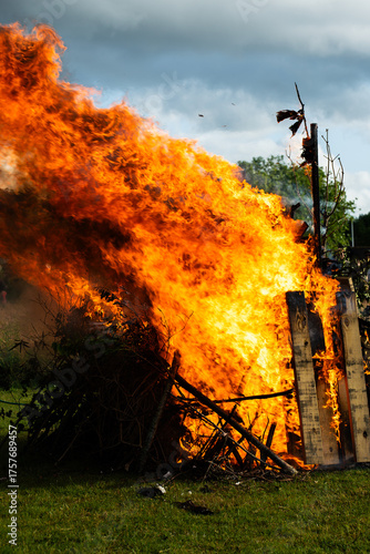 Close up of large local bonfire on grass field vertical view and intense burning.
