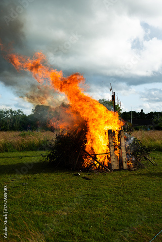 Large local bonfire on grass field vertical view and intense burning.
