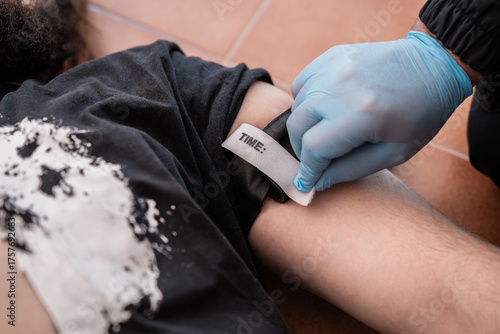 Paramedic placing tourniquet on injured man to stop bleeding during first aid