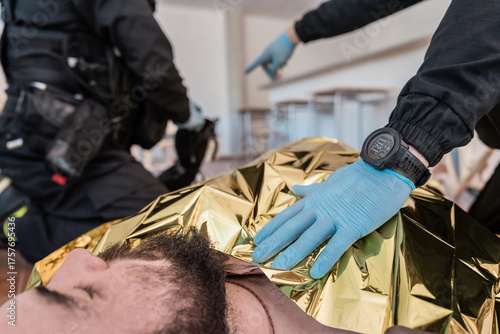 Billede på lærred Paramedics covering injured person with thermal blanket during rescue operation