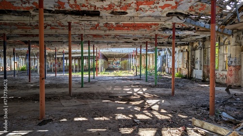 Derelict disused factory. Abandoned old industrial warehouse vibrant colours, peeling paint ceiling, sunlight shadows. Decaying construction building interior columns. Empty crumbling structure ruin.