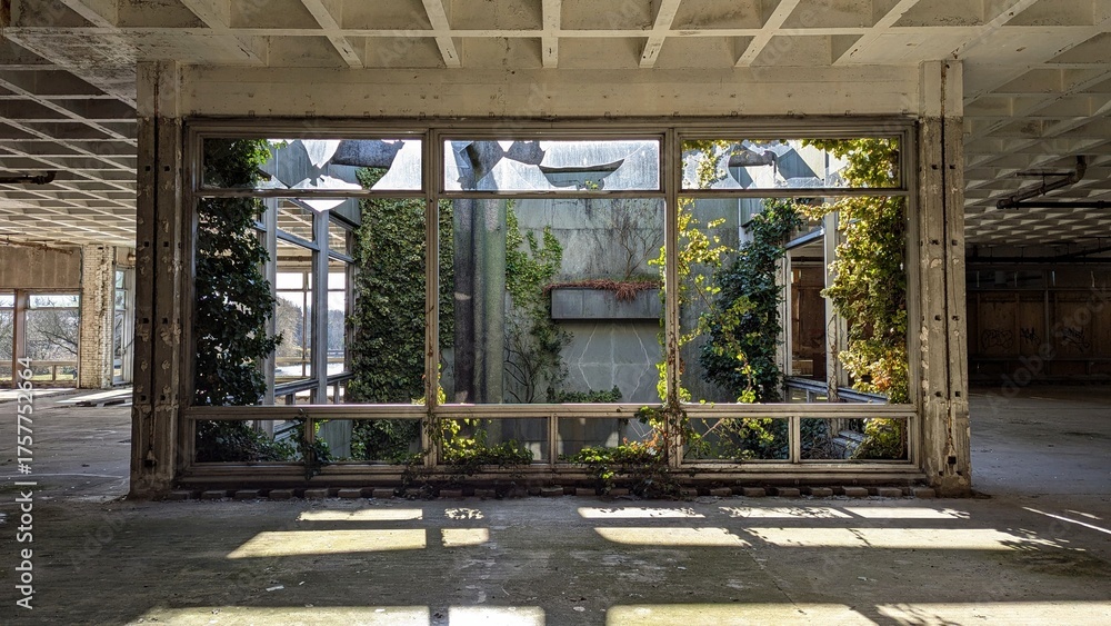 Fototapeta premium Terrarium inside derelict factory warehouse. Indoor garden, sun-light, shadows, deserted industrial architecture. Post apocalyptic desolate building. Empty wasteland, greenery, nature reclaiming.