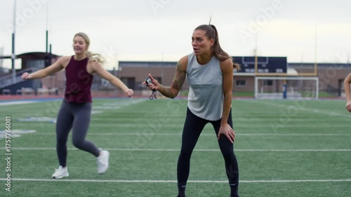 A focused group exercise session on a sports field, led by an enthusiastic coach motivating athletes with intense energy.