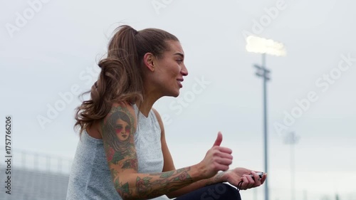 An athletic instructor passionately coaches her students on the field while holding a stopwatch.