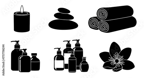 Spa elements lit candle, stacked stones, rolled towels, bottles, and flower