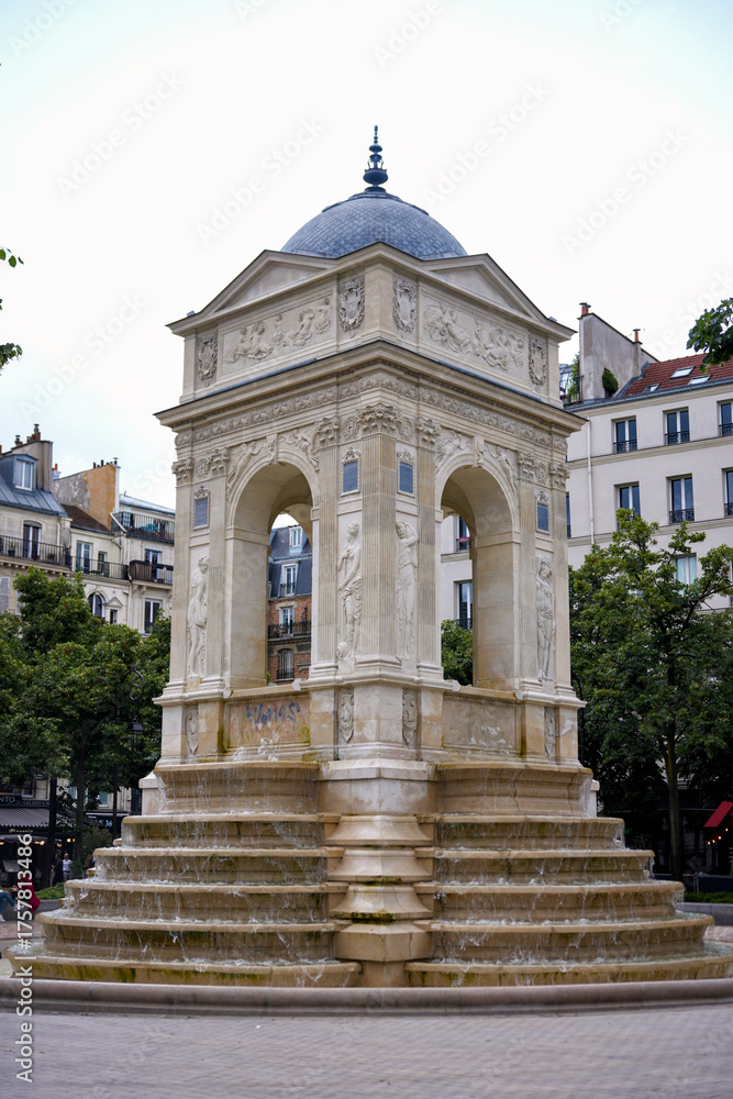 Fototapeta premium Fountain with decorative arches and sculptures in Paris France Classic European architecture and urban landmark surrounded by city buildings on a cloudy summer day