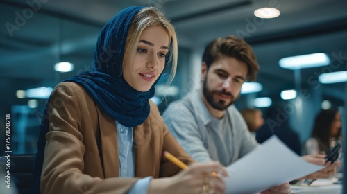 Businesswoman Wearing Hijab Collaborating with Colleagues on Project in Modern Office Environment