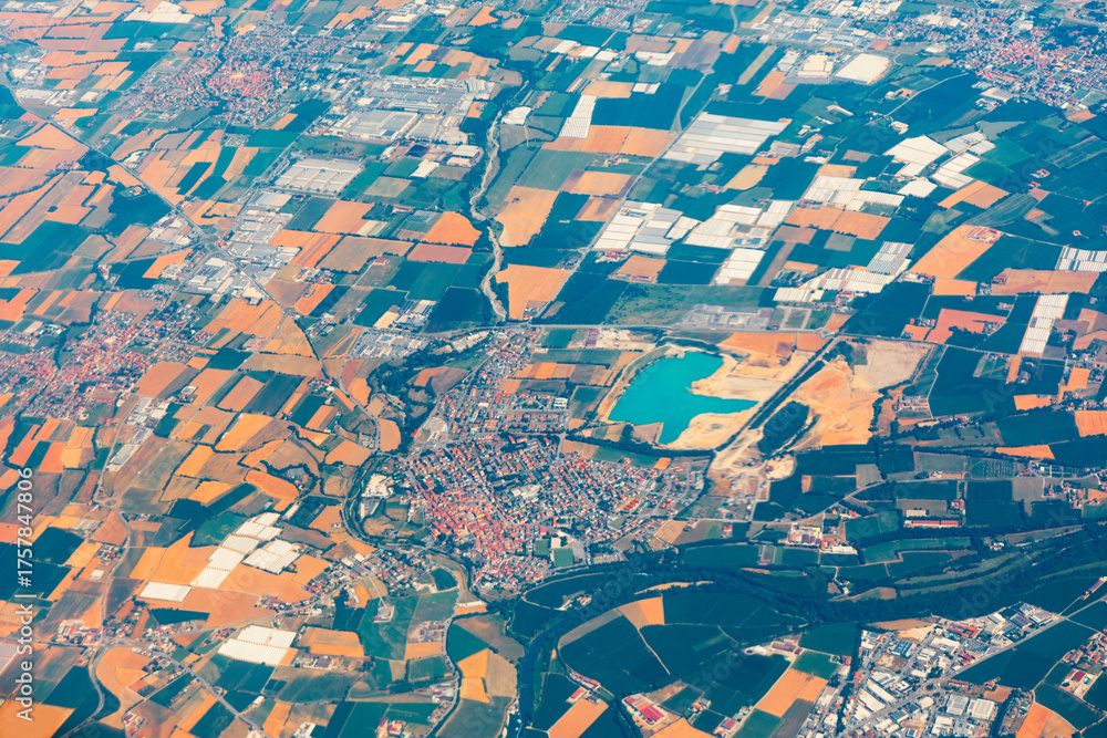 Obraz premium Aerial view of mixed terrain showing patchwork farmland, urban clusters, and a vivid turquoise reservoir. Winding river cuts through lush vegetation, highlighting diverse land use and natural features