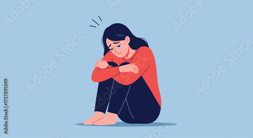 Young woman feeling sad and alone sitting with knees hugged to her chest.