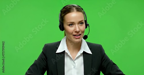 Smiling woman with headset in a suit against a green background.