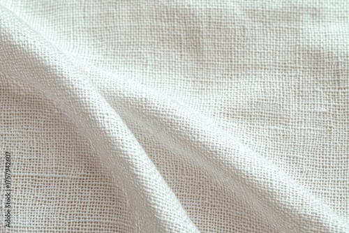 Close-up of a white textured fabric with visible woven grid pattern and gentle folds creating soft shadows