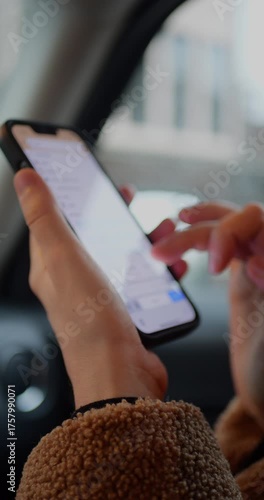 Close-up of hands using a smartphone in vertical orientation, typing or messaging inside a car. Mobile device, modern communication, and on-the-go digital lifestyle are captured.