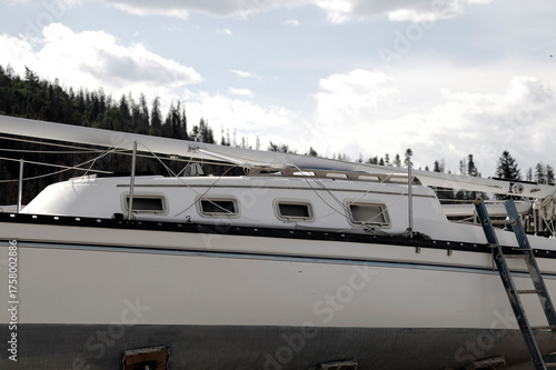 Sailboat deck and hull under construction white yacht exterior detail with rigging and ladder outdoor marine project