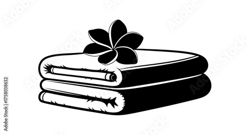 Two neatly folded towels topped with a single plumeria flower in black and white