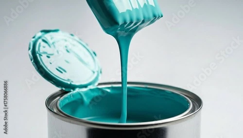Paintbrush dripping vibrant turquoise paint into an open can, close-up shot.