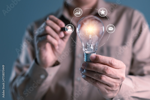 Businessman holding glowing light bulb with digital innovation icons, representing idea creation, business growth, leadership, problem solving, and strategy